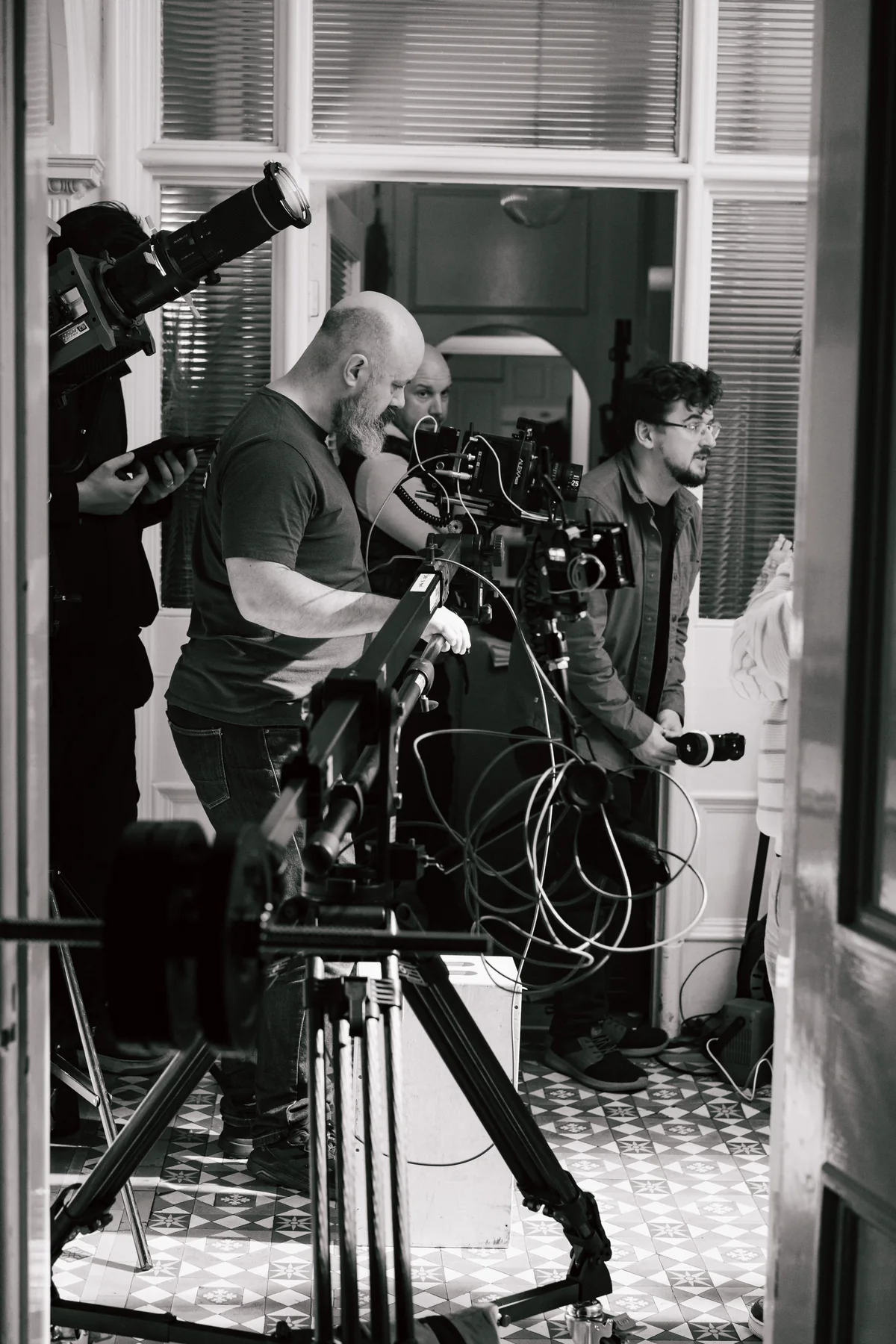 A black-and-white production photograph of a camera crew on set