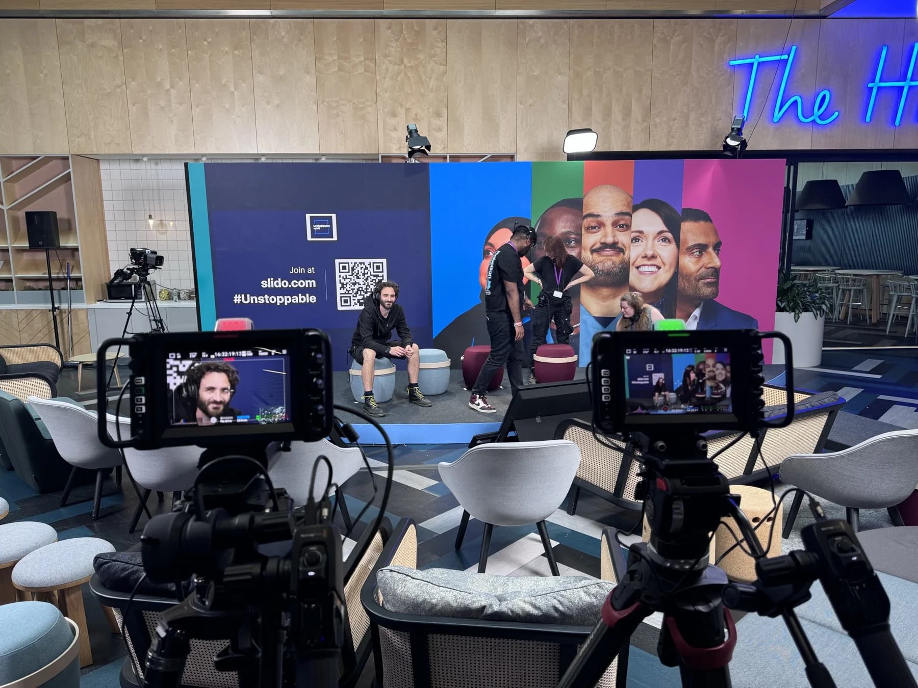 Two camera positions filming a speaker on a colourful event set