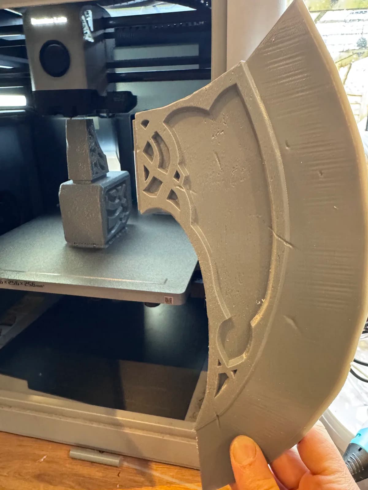 Unpainted 3D-printed fantasy axe head being trimmed in the workshop