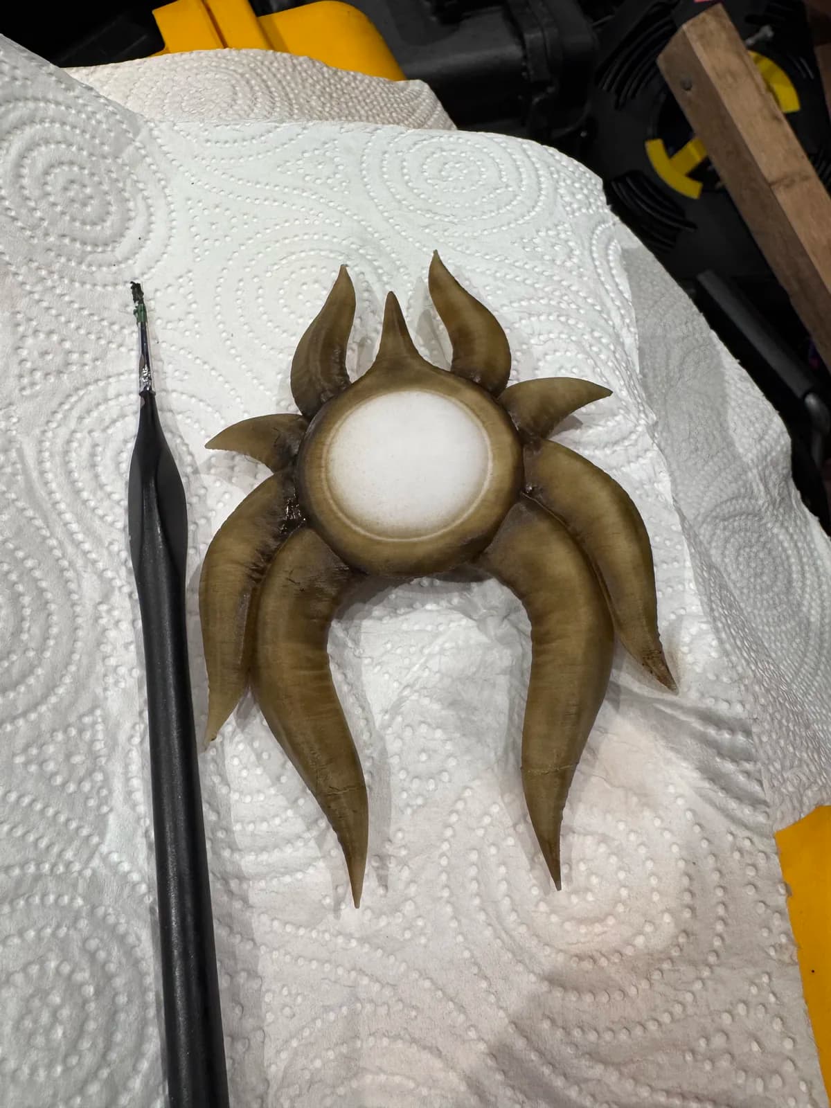 Painted crescent-shaped fantasy pendant resting on a paper towel