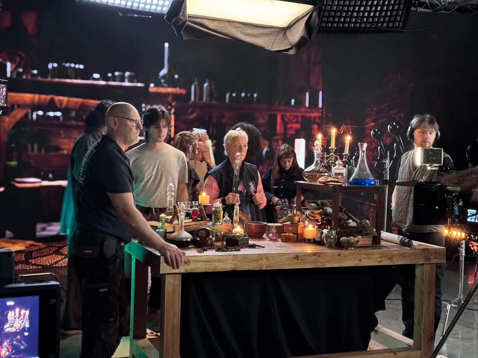 Cast and crew around a prop-filled table on the fantasy production set