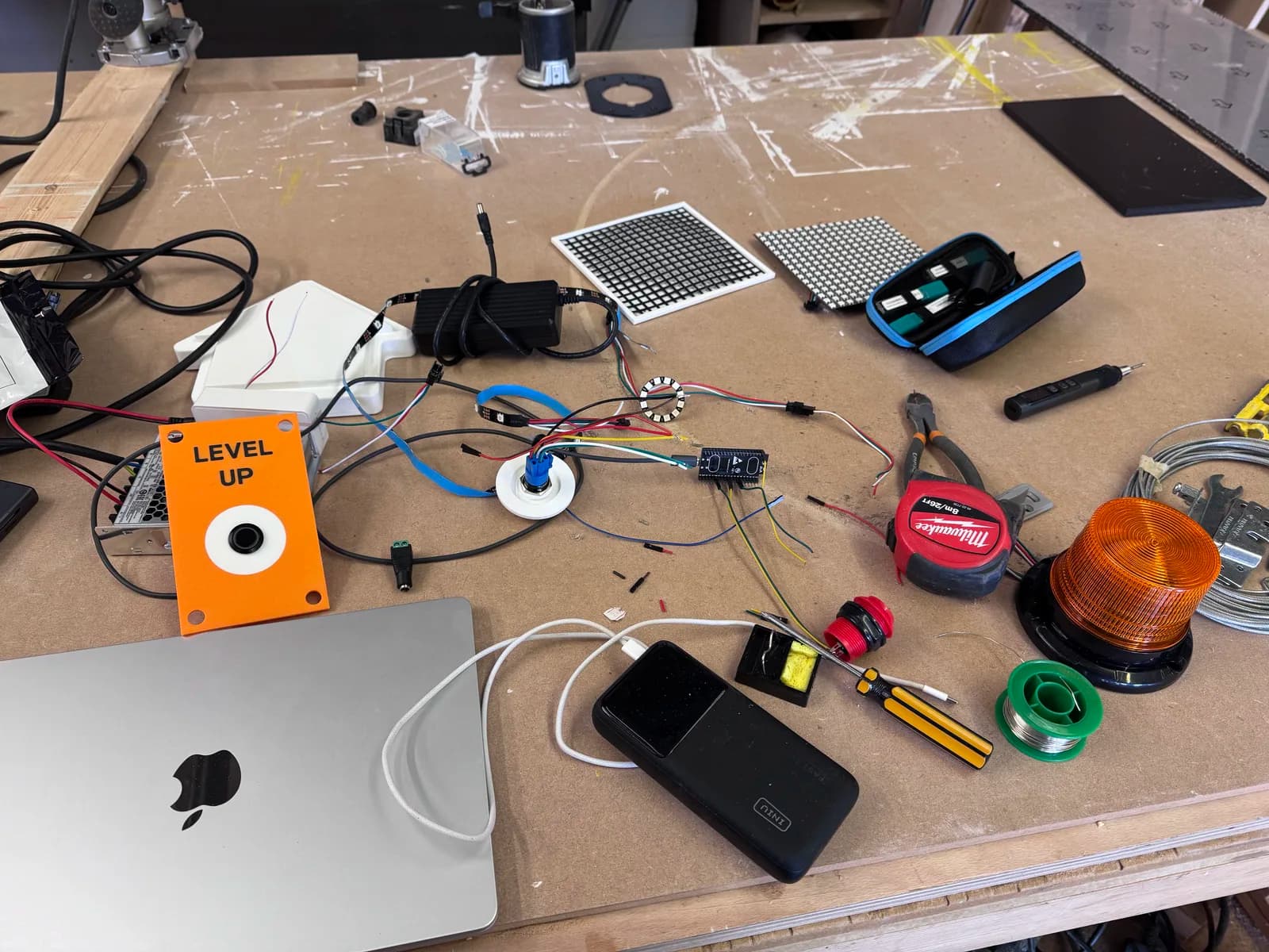 Lift button, wiring, controller boards and an amber beacon laid out on a workbench