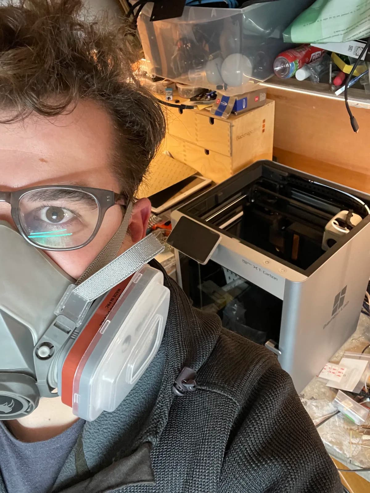 Workshop photograph beside a 3D printer with protective mask and glasses