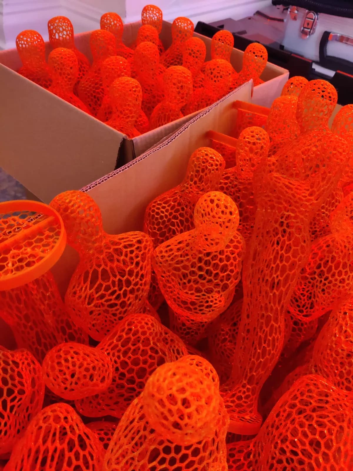 Rows of orange open-lattice award figures packed together before delivery