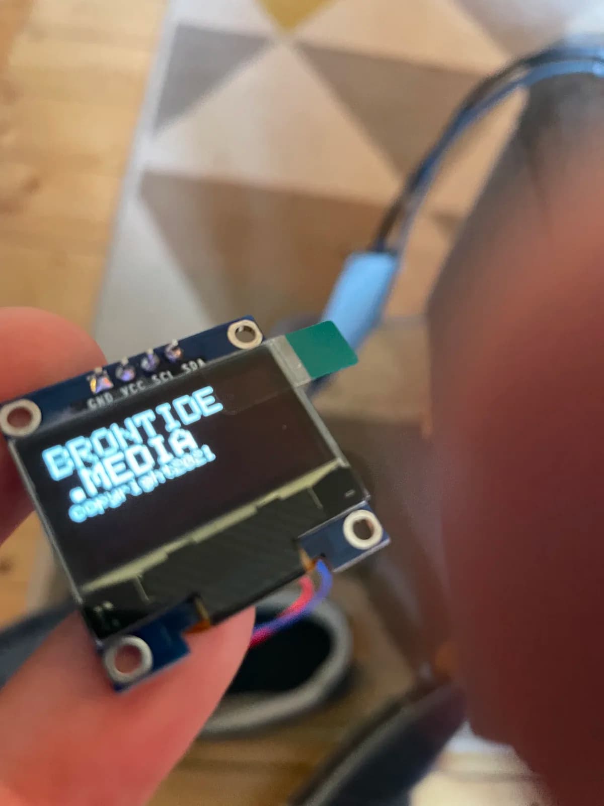 Small screen displaying Brontide Media on a circuit board held in one hand