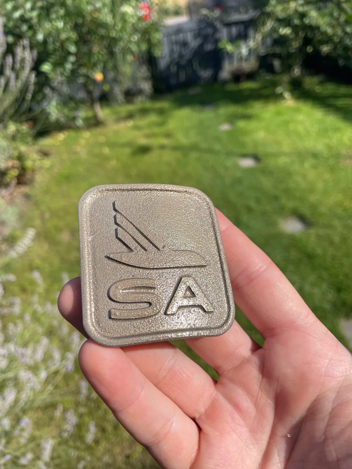 Textured SA emblem held outdoors before installation