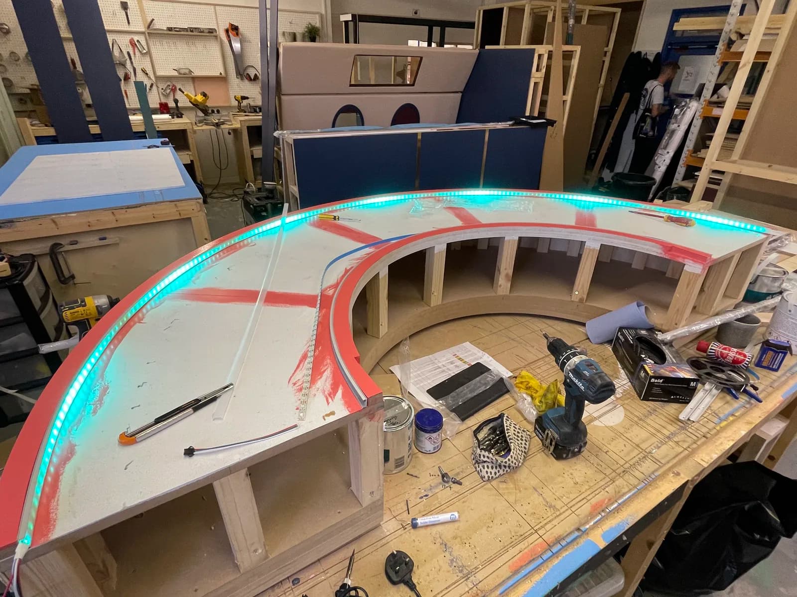 Large curved timber set piece with its edge lighting switched on in the workshop