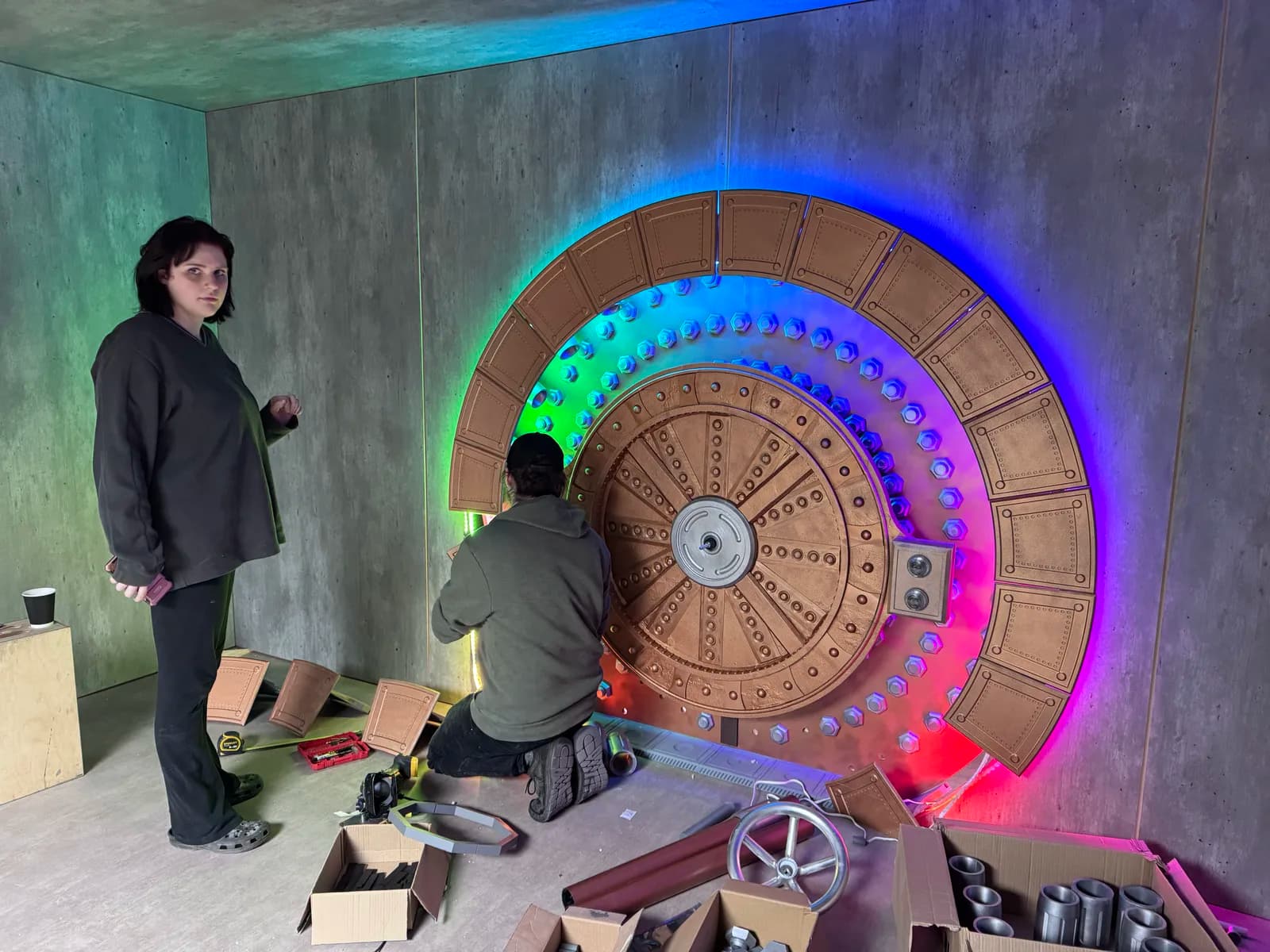 Two crew members fitting the illuminated vault door into the set